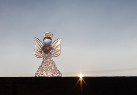 Souvenir angel against the backdrop of the sunset sky, the last ray of sunshine. Symbol of faith, hope. Angel Dayの写真素材
