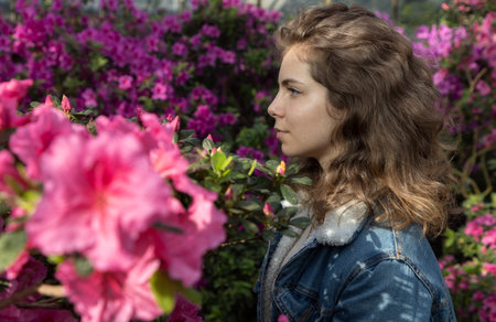 beautiful young woman or adult teenage girl about 18 years old, portrait in profile among flowering azalea bushes in botanical garden. A moment of inspiration and happiness. Enjoy the beauty of natureの写真素材