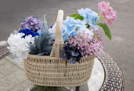lush bouquet of artificial flowers of multi-colored hydrangea in a beautiful wicker basket on a...