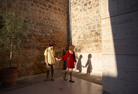 A young couple, a guy and a girl, holding hands, watching their shadow on a walk. Spending a sunny day together. First love, youthの写真素材