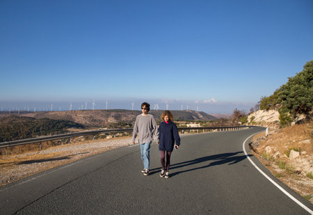 teenagers - girl and boy walking together on asphalt road on sunny vacation day. Youth, walks, joy, adventures, enjoying sunny day. Spending time together on vacationの写真素材