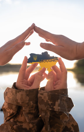 Hands of a Ukrainian soldier holding a souvenir map of Ukraine. Concept of protection, assistance to the people of Ukraineの写真素材