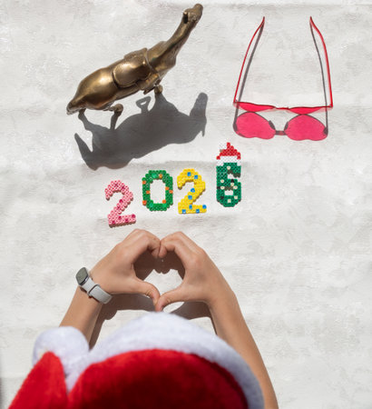 Multicolored numbers 2026, a child's hands folded into a heart shape, a souvenir horse as a symbol...