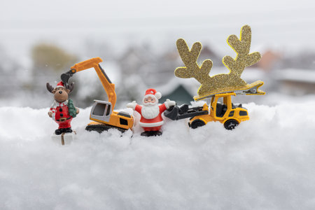 New Year's business greeting concept for a construction company. Toy models of an excavator and loader, a souvenir Santa Claus, and holiday decor with space for advertising inscriptions in the snowの写真素材