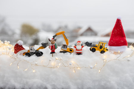 Christmas composition of toy excavators and holiday souvenirs in the snow among garlands. Winter weather. Concept for Christmas business greetings, New Year's celebrations in construction companiesの写真素材