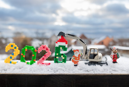 toy excavator, souvenir Santa Claus, the numbers 2026 stand in the snow outdoors. Cold winter weather. Concept for Christmas business greetings and New Year's celebrations in construction companiesの写真素材