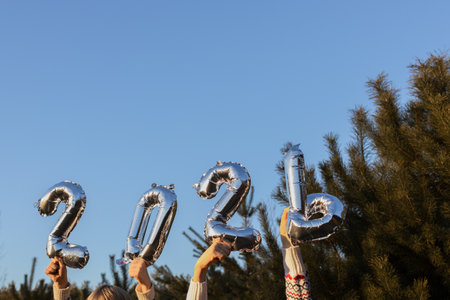 Silver numbers 2026 from air balloons in hands on the background of the sky. New plans and dreams....