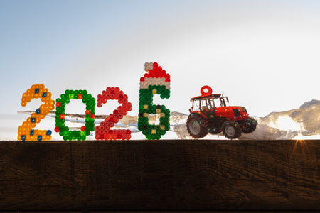 childrens toy souvenir shaped like a tractor and the New Year 2026 numbers in the rays of the setting sunの写真素材