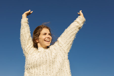 freedom-loving, happy young European woman in her 20s enjoying a moment outdoors on a sunny day against a cloudless sky. Love life, well-being, positive thinking.の写真素材