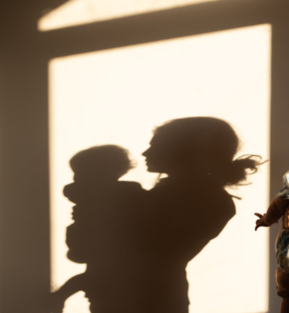 Silhouettes of a mother and baby on a wall, shadows of people illuminated by the sun. Happy Mothers Dayの写真素材