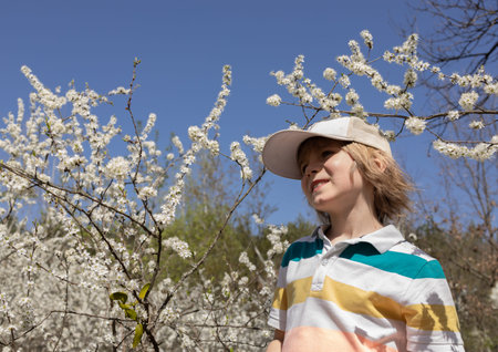 portrait of a sweet boy in a cap walking in the park on a sunny spring day. A happy childhood, a...