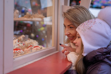 Mom and daughter choose, buy souvenirs at the Christmas marketの写真素材