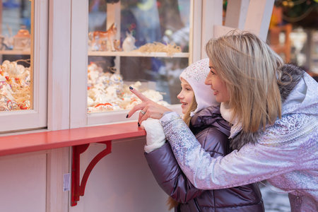 Mom and daughter choose, buy souvenirs at the Christmas marketの写真素材