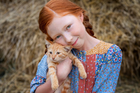 redhead girl holding a ginger kitten in her armsの写真素材