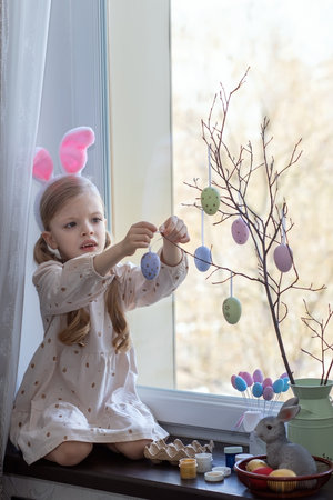 A preschool girl paints eggs for the bright holiday of Easterの写真素材