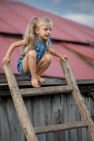 Beautiful little girl model sitting on the stairs on the roofの写真素材