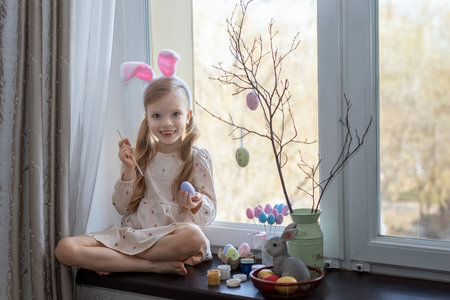 Joyful little girl paints eggs for Easter holidays. Happy Easter.の写真素材