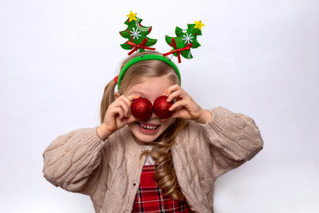 Portrait cute girl with christmas decorative balls on her eyes. New Year's festive mood.の写真素材