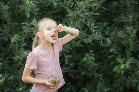 Little girl eating white currants off stem, smiling at cameraの写真素材
