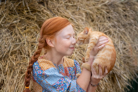redhead girl holding a ginger kitten in her armsの写真素材