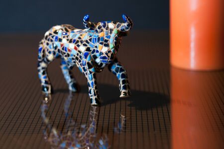colorful ceramic bull on a glass table and orange detail in the backgroundの写真素材