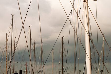 Masts and many ropes of sailing boats standing in harbor. Graphic image with oblique and vertical...