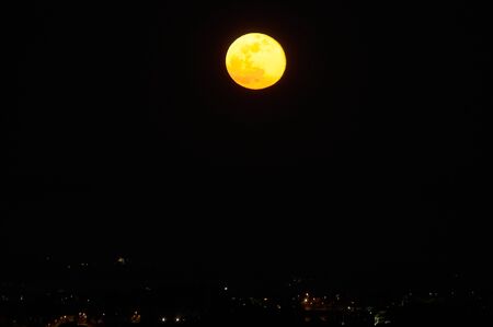 full red moon in the dark sky and city lights