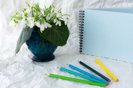 Bouquet of snowdrop flowers in glass vase, isolated on white. Spring still life with creative materials, spring background with colored pencilsの写真素材