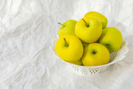 Yellow apples on a plate on a white paper background, still life with apples, Golden Applesの写真素材