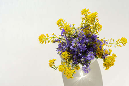 Spring flowers in a vase top view. Beautiful yellow and purple flowers in a glass vase. Flowers on a white backgroundの写真素材