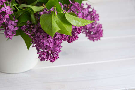 Lilac in a vase on a white background close-up. A bright bouquet of lilac on a wooden table. Spring...
