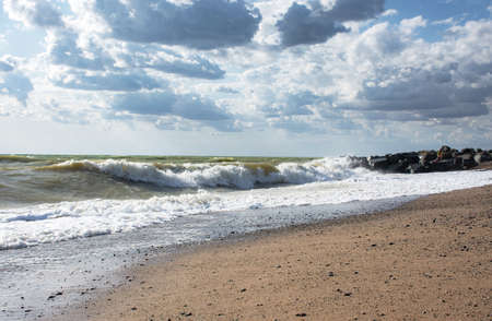 Big waves roll up on the beach. Bright Sunny day and sea surf. White foaming waves and splashes. Beach during a storm. A hot summer day and a stormy sea. High wave. Cloudy seascape.の写真素材