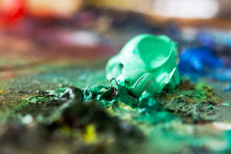 Aquamarine oil paint close-up on the artist's palette. Hobbies and leisure. The mixing of paints....