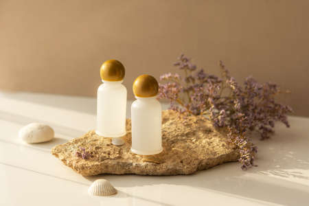 Cosmetic bottles on a natural background. Warm beige shades of stone and background in the sunlight....