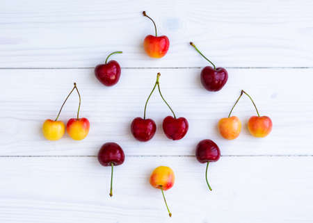 Composition of cherries on a white wooden background top view. The concept of the layout of the...