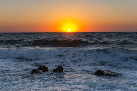 Sunset and storm at sea. Large waves against the background of the setting sun. Summer storm on the...