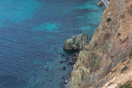 View from the cliff down to the sea. Beautiful turquoise sea water. Rocky coast close-up. The black sea in Crimea. Cape Fiolent Sevastopol.の写真素材