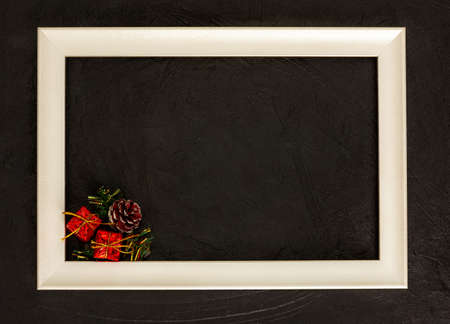 New year greeting card from a frame and decorations on a black background. Top view of a white frame...