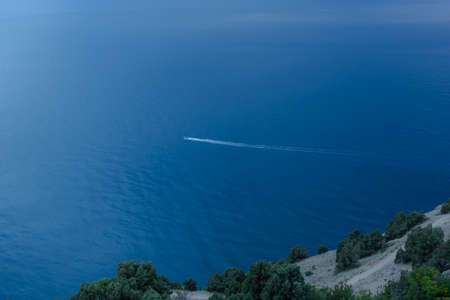 A lone boat in the endless blue sea. Top view of the sea background with the ship. The concept of...