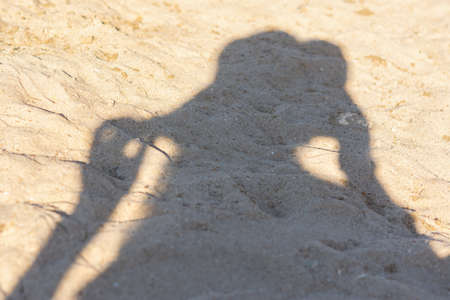 Shadow of a girl in a hat on the beach. Trendy light beige iridescent color Set Sail Champagne on...