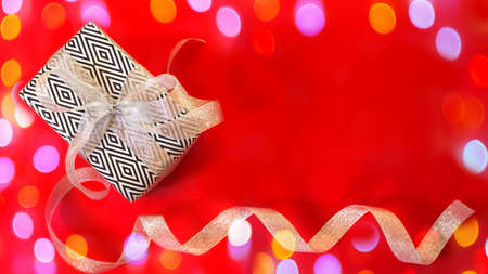 New year's gift on a red background. Merry Christmas and happy New year. Colorful bright design. Black and white gift packaging. Christmas background top view, flat layout, banner, card, copy spaceの写真素材