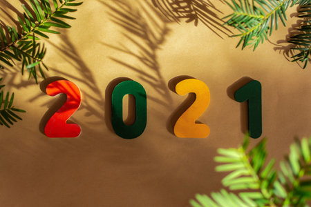 Wooden multi-colored numbers 2021 on a beige background with beautiful shadows from the Christmas tree. Trendy colors Tidewater Green, Fortuna Gold and Set Sail Champagne. Warm Christmas backgroundの写真素材