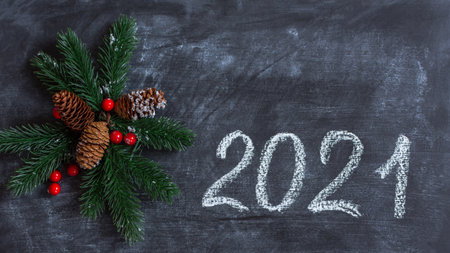 Christmas decorations 2021 on a chalkboard. The concept of a New year. Cones, fir branches, red...