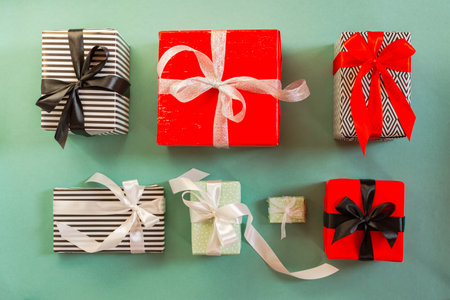 Christmas gifts on a green background. Different packed boxes with tied bows top view. happy new year and christmas. the concept of shopping, gifts for the holidays. Flat lay.の写真素材
