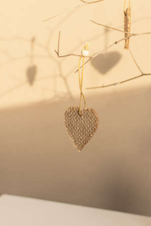 Creative composition in neutral colors for Valentine's Day. Hearts on a branch in a vase on the table. Handmade, coarse burlap fabric. Warm home atmosphere, romantic greeting card with space for textの写真素材