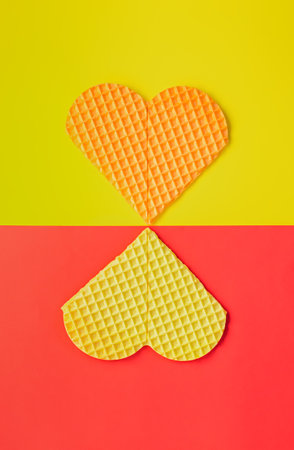 Figure 8 of waffle hearts on a red and yellow background. Creative composition for the International Women's Day, Valentine's Day. Spring greeting card design, love concept. Minimalism, flat layoutの写真素材
