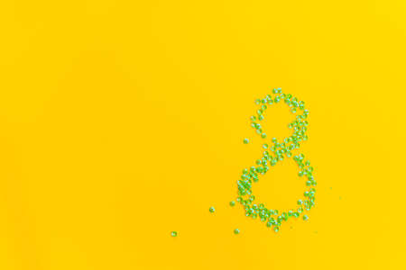 The number 8 on a yellow background. A creative composition of shiny jewelry for the International...