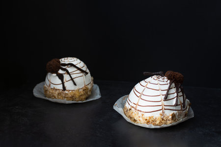 Halloween cake. Chocolate cream cupcakes on a black background. Scary drawing of a spider with chocolate chips. Sweet festive design. Funny children's cakes in selective focus. Hello, Halloween.の写真素材