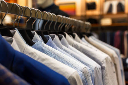 Shirts shopping close-up on hangers. Men's clothing store with a variety of autumn-winter goods to choose from. The range of goods in the boutique. The concept of sales, promotions, Black Fridayの写真素材