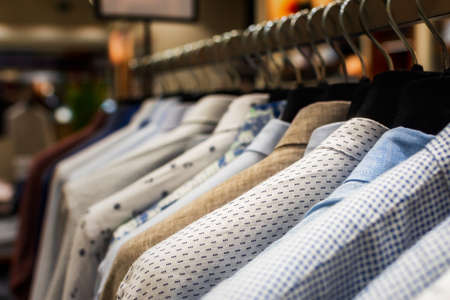 Shirts shopping close-up on hangers. Men's clothing store with a variety of autumn-winter goods to...